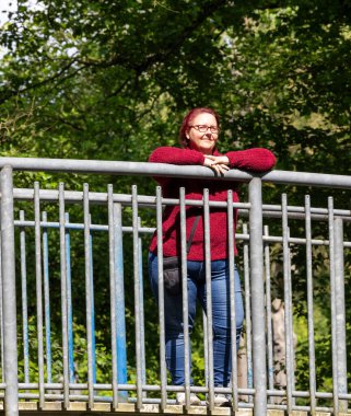 Güneşli bir yaz gününde, ormanda kızıl saçlı neşeli bir kadının portresi.