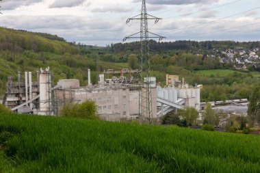 Büyük bir sanayi fabrikası bir çim tarlasının yanındaki yamaçta bulunur.