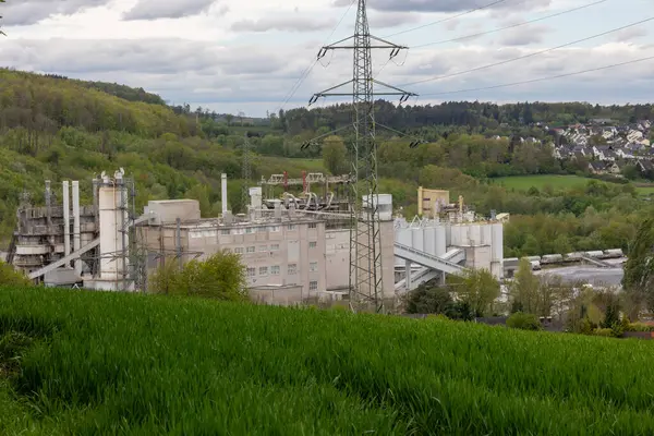 Büyük bir sanayi fabrikası bir çim tarlasının yanındaki yamaçta bulunur.