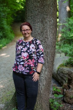 Kırsalda bir ağacın yanında duran düşünceli kadın.