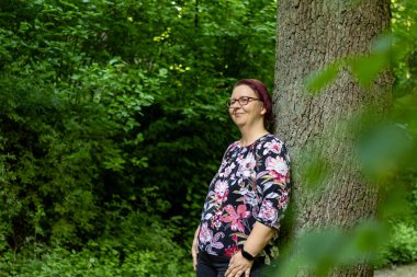 Kırsalda bir ağacın yanında duran düşünceli kadın.