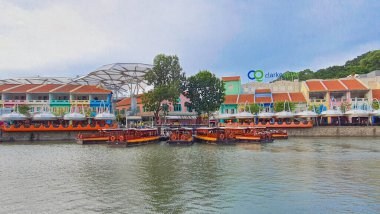 Singapur - 01 Ocak 2023: Günbatımında Clarke Rıhtımı, arka planda renkli geleneksel Çin Peranakan dükkanları ile Singapur Nehri 'ni boydan boya gezen tekne manzarası