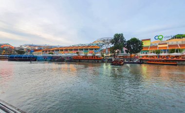 Singapur - 01 Ocak 2023: Günbatımında Clarke Rıhtımı, arka planda renkli geleneksel Çin Peranakan dükkanları ile Singapur Nehri 'ni boydan boya gezen tekne manzarası