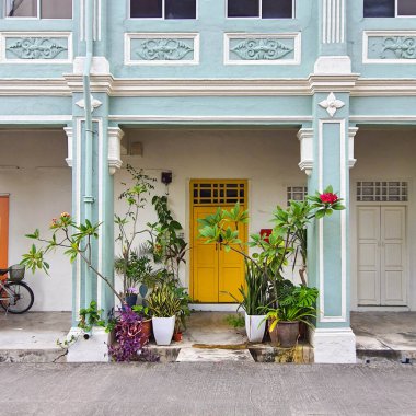 Singapur, Ocak 03 2023: Kenarlarında çiçek saksıları olan geleneksel bir Çin mimarisinin parlak sarı kapısı
