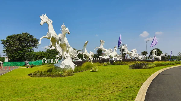 Tangerang, Endonezya - 31 Mayıs 2023: Görkemli beyaz atların heykeli açık mavi bir gökyüzüne karşı yeşil çimlerin üzerinde zıplıyor