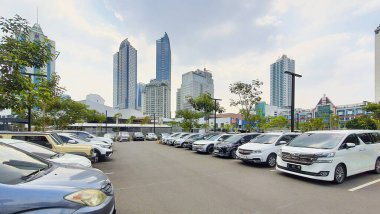 Jakarta Endonezya - 22 Ağustos 2023: Şehir merkezinin ortasında ağaçlar, gökdelen binaları ve birçok arabanın bulunduğu güneşli bir gün