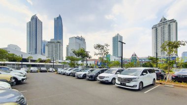 Jakarta Endonezya - 22 Ağustos 2023: Şehir merkezinin ortasında ağaçlar, gökdelen binaları ve birçok arabanın bulunduğu güneşli bir gün