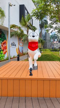 Cakarta Endonezya - 22 Ağustos 2023: Ahşap bir kaide üzerinde hoplayıp zıplayan Sibirya Husky köpek heykeli çizimi Satrio Strip Alışveriş Merkezi Kuningan 'da yemyeşil manzaralı kırmızı bir eşarp takıyor.
