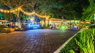 Jakarta 22 Ağustos 2023: Geceleri Şehir Ormanı Cipete 'deki restoranlar, güzel ışıklandırma, perili ışıklar, kaldırım taşı patikası, verimli peyzaj, açık hava piknik masaları. Parkta yemek yemek.