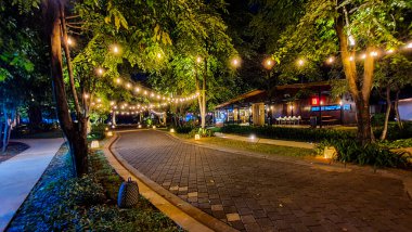 Jakarta 22 Ağustos 2023: Geceleri Şehir Ormanı Cipete 'deki restoranlar, güzel ışıklandırma, perili ışıklar, kaldırım taşı patikası, verimli peyzaj, açık hava piknik masaları. Parkta yemek yemek.