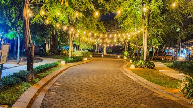 Jakarta 22 Ağustos 2023: Geceleri Şehir Ormanı Cipete 'deki restoranlar, güzel ışıklandırma, perili ışıklar, kaldırım taşı patikası, verimli peyzaj, açık hava piknik masaları. Parkta yemek yemek.