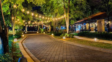 Jakarta 22 Ağustos 2023: Geceleri Şehir Ormanı Cipete 'deki restoranlar, güzel ışıklandırma, perili ışıklar, kaldırım taşı patikası, verimli peyzaj, açık hava piknik masaları. Parkta yemek yemek.