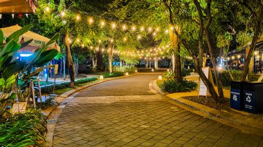 Jakarta 22 Ağustos 2023: Geceleri Şehir Ormanı Cipete 'deki restoranlar, güzel ışıklandırma, perili ışıklar, kaldırım taşı patikası, verimli peyzaj, açık hava piknik masaları. Parkta yemek yemek.