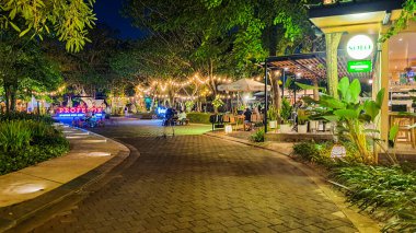 Jakarta 22 Ağustos 2023: Geceleri Şehir Ormanı Cipete 'deki restoranlar, güzel ışıklandırma, perili ışıklar, kaldırım taşı patikası, verimli peyzaj, açık hava piknik masaları. Parkta yemek yemek.
