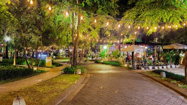 Jakarta 22 Ağustos 2023: Geceleri Şehir Ormanı Cipete 'deki restoranlar, güzel ışıklandırma, perili ışıklar, kaldırım taşı patikası, verimli peyzaj, açık hava piknik masaları. Parkta yemek yemek.