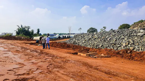 Kırmızı toprakta yol malzemesi olarak kullanılan ezilmiş taş moloz yığını. İnşaat alanındaki açık mavi arka plana karşı.