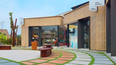 Jakarta Nov 01 2023: Endonezya Tasarım Bölgesi PIK2 'deki açık hava alışveriş merkezinin yakınındaki sevimli sarı rattan mağazaları olan dairesel asfalt plaza.