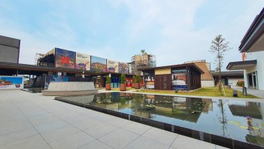 Jakarta Nov 01 2023: su zambaklarıyla dolu bir göletin önündeki beton bank ve saksı. Arkadaki binalar. simetrik yansıma Endonezya Tasarım Bölgesi PIK 2