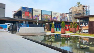 Jakarta Nov 01 2023: su zambaklarıyla dolu bir göletin önündeki beton bank ve saksı. Arkadaki binalar. simetrik yansıma Endonezya Tasarım Bölgesi PIK 2