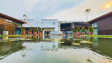 Jakarta Nov 01 2023: Beton bank ve su zambaklarıyla dolu bir havuzun önündeki saksı görüntüsü. Arkadaki binalar. simetrik yansıma Endonezya Tasarım Bölgesi PIK 2