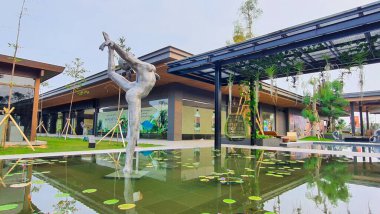 Jakarta Nov 01 2023: Yansıyan bir gölette yüzen balerin çelik sanatının ön çekimi. Nilüferler, tropik bitkiler. Balonlar, günbatımı gökyüzü. Endonezya Tasarım Bölgesi açık hava alışveriş merkezi