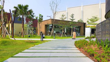 Jakarta Nov 01 2023: Arkasında bazı mağaza binaları ve Endonezya Tasarım Bölgesi PIK2 AVM 'de güzel tropikal peyzajı olan bir bahçede beton geçit.