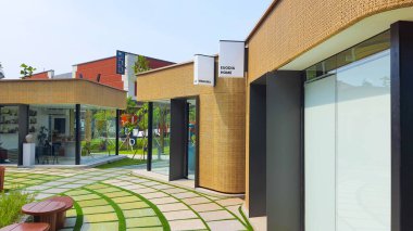 Jakarta Nov 01 2023: Endonezya Tasarım Bölgesi PIK2 'deki açık hava alışveriş merkezinin yakınındaki sevimli sarı rattan mağazaları olan dairesel asfalt plaza.