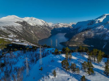 Norveç 'in dağları, gölü ve kardaki ağaçları olan elektrik hatlarının havadan görünüşü.