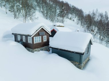 Dağlarda karla kaplı bir tepenin üzerindeki ahşap ev.