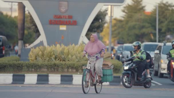 2023年12月12日 インドネシア 高齢の女性が密集した都市交通を通じて着用した自転車をペダルで走らせます スリランカの朝の道路の忙しい交通 — ストック動画