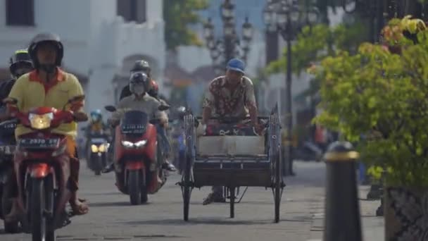 2023年12月13日 インドネシアのセマランが 歴史ある古い街を走り回るリックショーに乗った 運を求める彼の探求では 老人は乗客を探している大都市の賑やかな通りをナビゲートします — ストック動画
