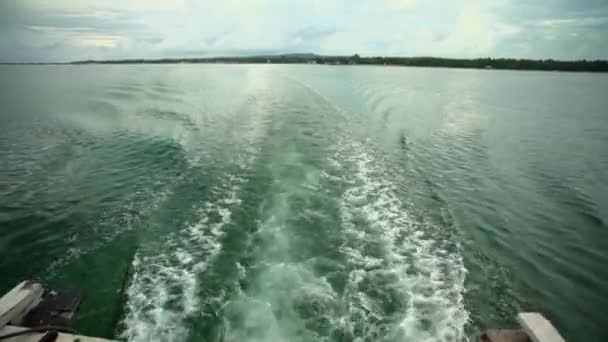 緑の海と青の空 白い雲と遠い島のスピードボートのエンジンからの波 — ストック動画