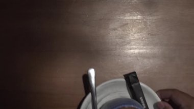 Bir fincan sıcak çikolatanın üst açılı çekimi ahşap bir masanın üzerine zarif bir şekilde yerleştirilmiş mavi bir seramik bardakta sunuluyor..