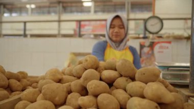 Wonosobo, Endonezya, 11 Aralık 2023 - Bir patates satıcısı ürünlerini geleneksel pazarda düzenliyor
