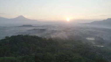 Güneşin doğuşuyla birlikte sislerin ve dağların havadan çekilmiş görüntüleri. Sihirli bir sabah sisi üzerinde destansı bir uçuş.