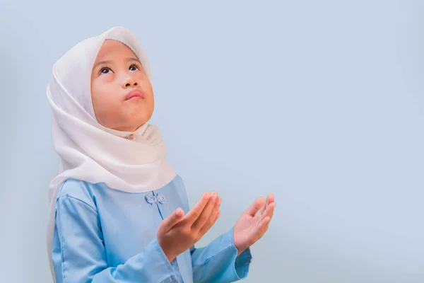 İslami kıyafet olarak başörtüsü takan Asyalı küçük bir kız. Küçük Asyalı Müslüman kız ciddiyetle dua ediyor. Küçük Asyalı kız el dua ediyor. Ramazan Kareem