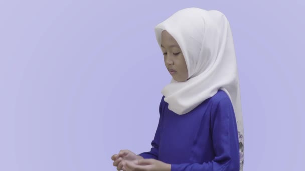 ヒジャーブのイスラム教徒の少女は 青い背景の上に隔離された彼女の腕を熱心に開きます — ストック動画