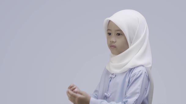 ヒジャーブのアジアのイスラム教徒の少女は灰色の背景の上に隔離された彼女の腕を熱心に開きます — ストック動画