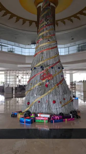 Altında bir sürü hediye bulunan büyük beyaz bir Noel ağacı süsü. Hediyeler ve dekorasyonlar