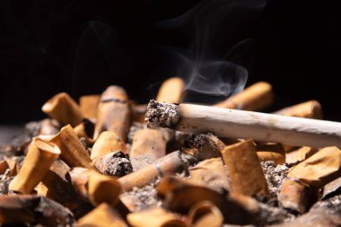 Kül tablasında yanan sigara ve dumanlı