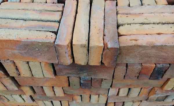 The red bricks in a big stack. These bricks are to be used for walls in the house