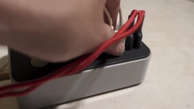 Erkek eli kabloları güç çıkışına bağlıyor. Cihazlar için modern çoklu port usb şarj cihazı. Aşırı yüklenmiş soket