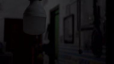 Bir el, düğme kablosunu çeker ve gece bir odanın ışığını açar. Enerji tasarrufu LED ampulleri