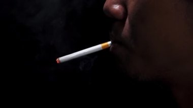 Siyah arka planda sigara içen bir adamın yan görüntüsü. Sigara içme alanı