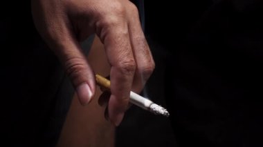 Elde sigara. Bir adamın eli sigarayı tutuyor ve duman yükseliyor. Sağlık, bağımlılık kavramları