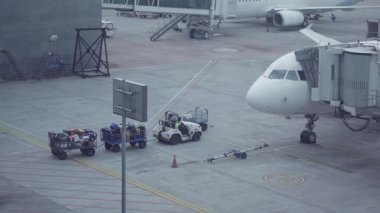 Yogyakarta, Endonezya - 1 Şubat 2025. Havalimanı pistinde yer ekibi ve bagaj malzemeleriyle birlikte bir uçak. Bagaj taşıyıcıları bagaj ile havayolu yükler.