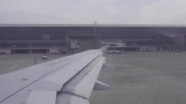 Yogyakarta Uluslararası Havalimanı, Endonezya - 1 Şubat 2025. Havayolu şirketi bulutlu pistten indi. Havaalanı binasının penceresinden görüntüle