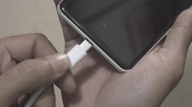 Akıllı telefona USB-C kablo makro eklentisi. Akıllı telefona beyaz USB kablosu yerleştiriliyor.