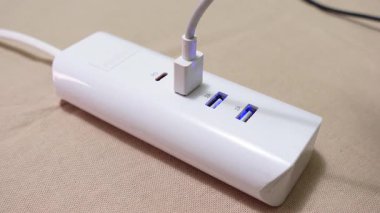 USB kablosunun CU 'su prize takıldı. Cihazlar için modern çok portlu USB şarj cihazı. USB Kablosu Beyaz Çokluport Şarj İstasyonuna Bağlanıyor