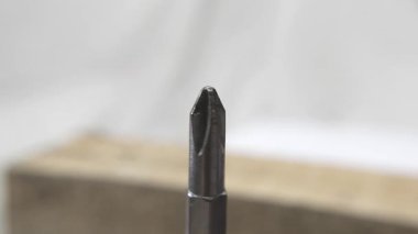 Elektronik tornavida parçasını döndürüp, metalik dokusunu bulanık bir arkaplana vurguluyorum.